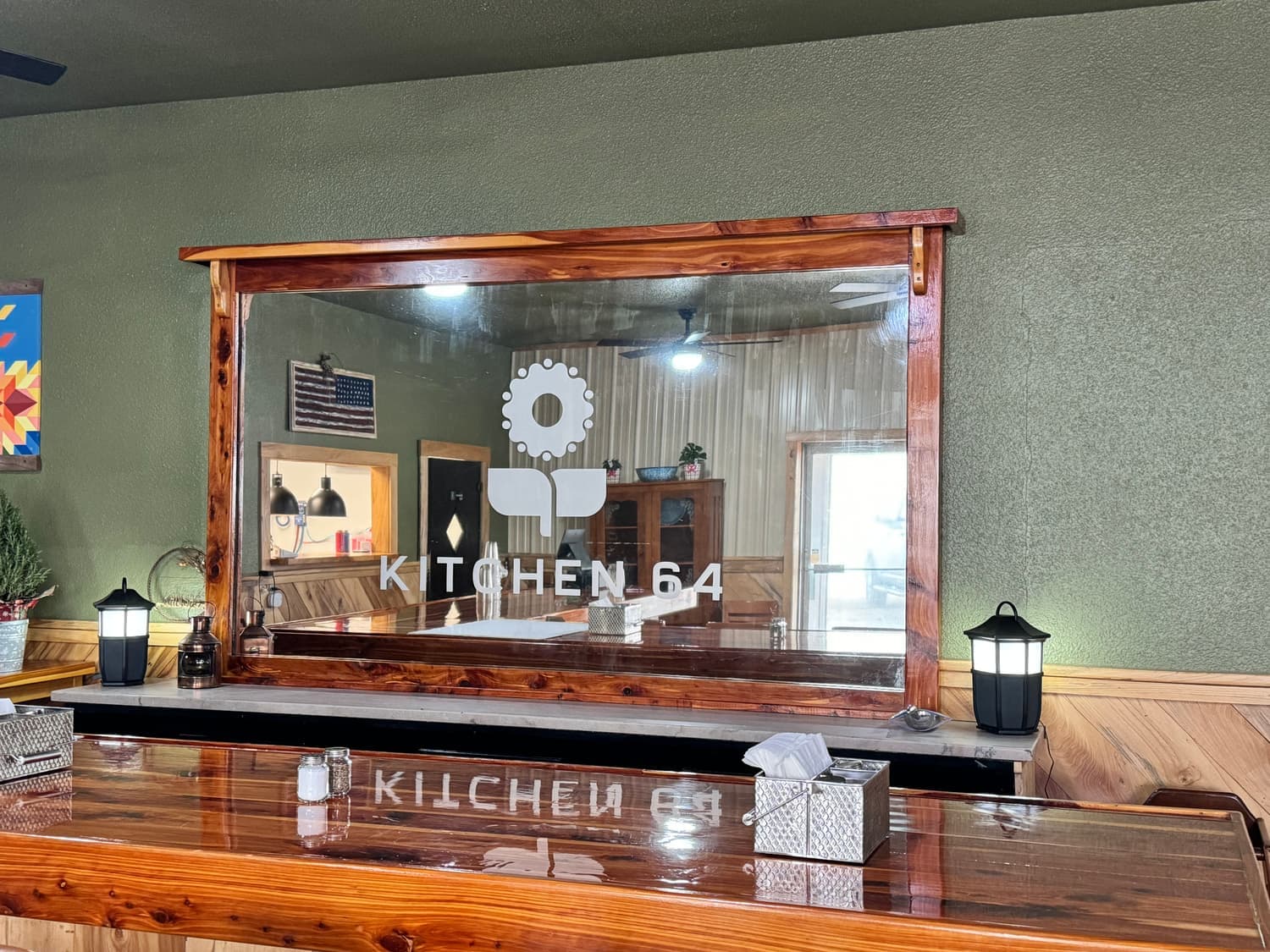 The cedar-framed mirror etched with the Kitchen 64 logo above the counter