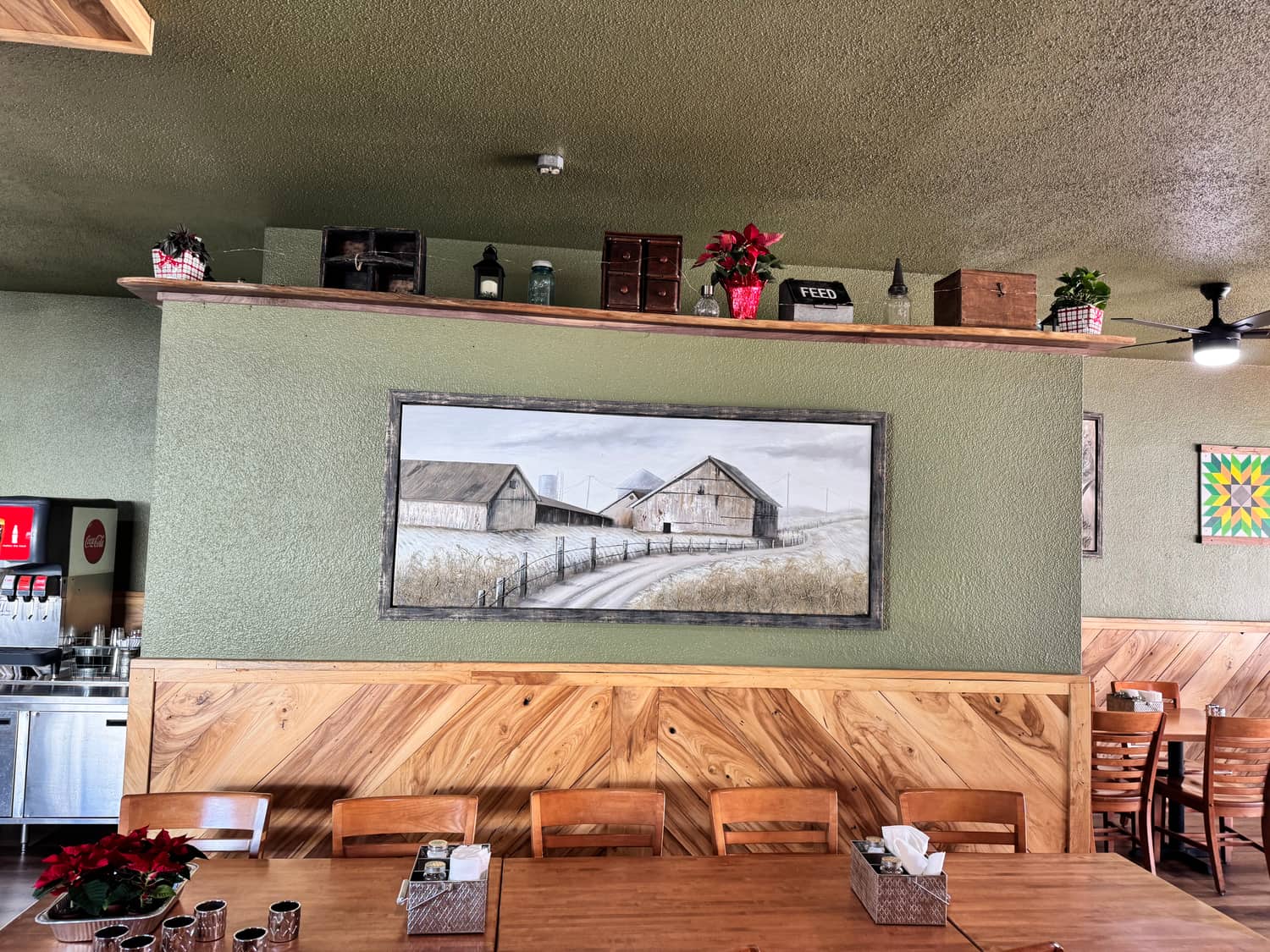 Framed barn artwork above the wood wainscoting along the Kitchen 64 dining room wall