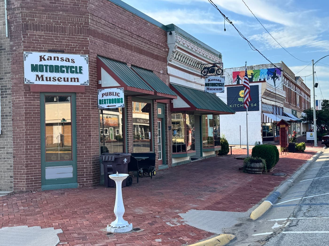 The Kansas Motorcycle Museum on the brick-paved corner of Washington Street in downtown Marquette, with the Kitchen 64 banner down the block